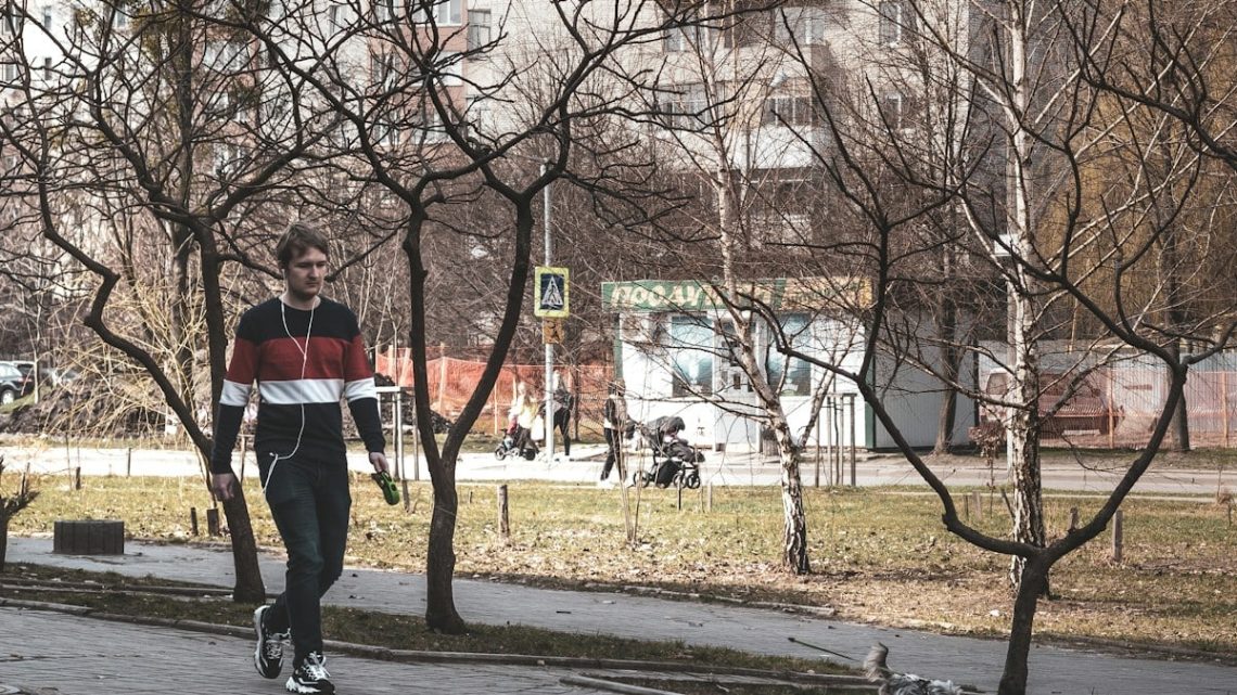 a man riding a skateboard down a sidewalk next to a park