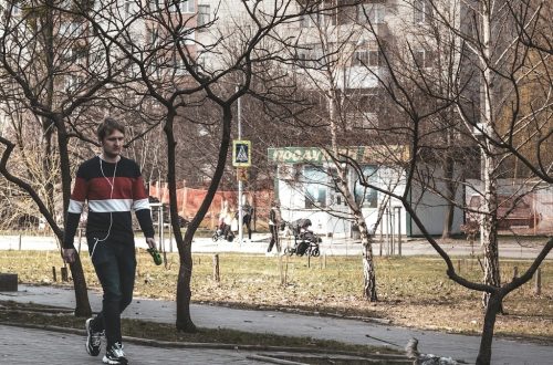 a man riding a skateboard down a sidewalk next to a park