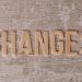 Wooden letters arranged to form 'Changes' on a textured, rustic surface.
